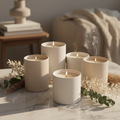 Luxury scented candles in matte ceramic vessels on marble surface with botanicals